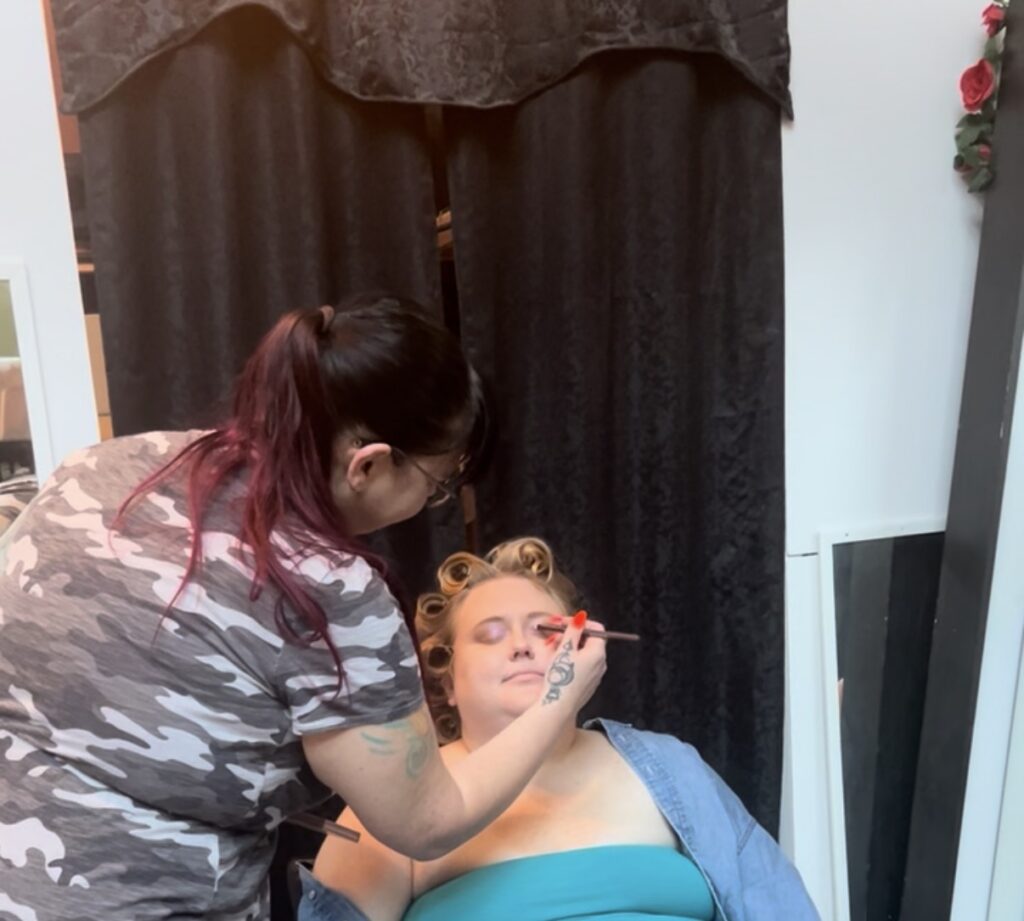 Lady sitting in chair getting her hair and makeup done for a boudoir session  in the photo studio in Minneapolis Mn. 