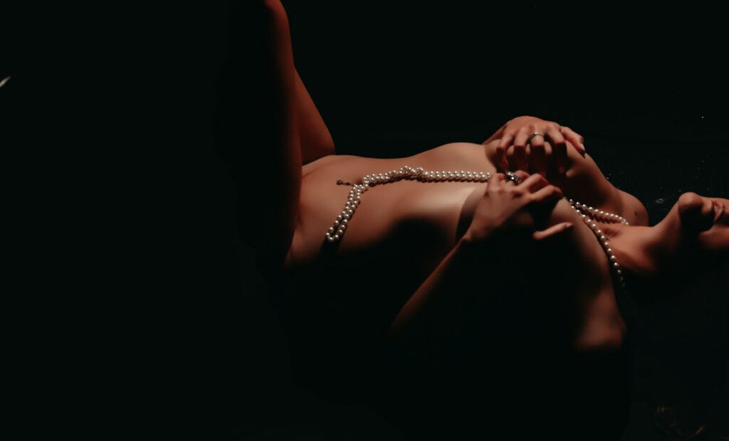 woman laying on the ground in Minneapolis Mn with just pearls. 