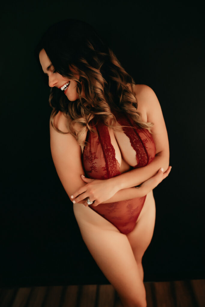 Woman standing and laughing in red lace lingerie. 