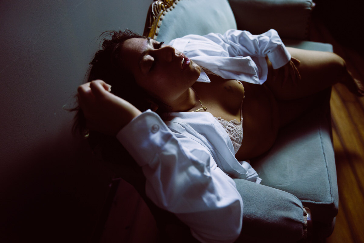 Woman laying on chaise with white button down shirt
