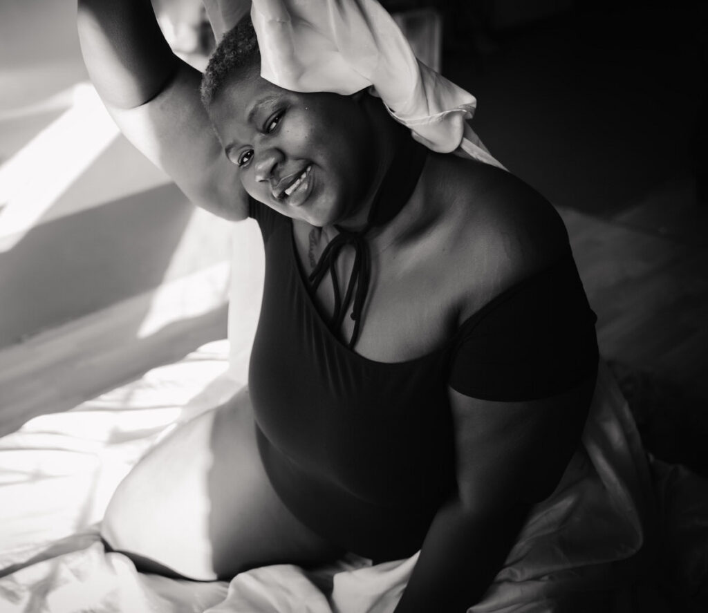 black and white image of a woman smiling and peeking out from behind a sheet at the photo studio in minneapolis mn. 